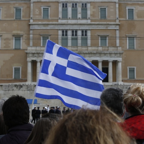Πολίτες κρατούν ελληνική σημαία μπροστά από τη Βουλή