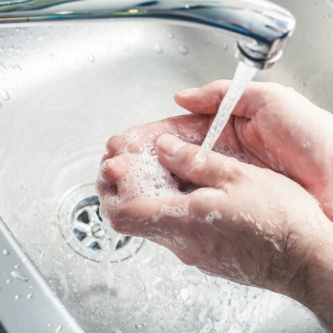 Άτομο πλένει τα χέρια του κάτω από τη βρύση