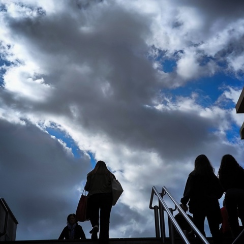 Πολίτες ανεβαίνουν τα σκαλιά - Φόντο ουρανός με μαύρα σύννεφα