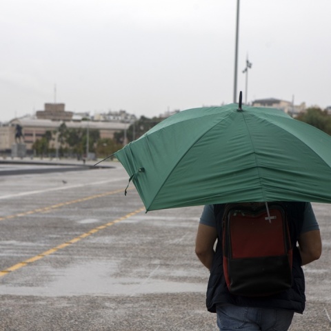 Άτομο με ομπρέλα περπατά στην παραλία Θεσσαλονίκης