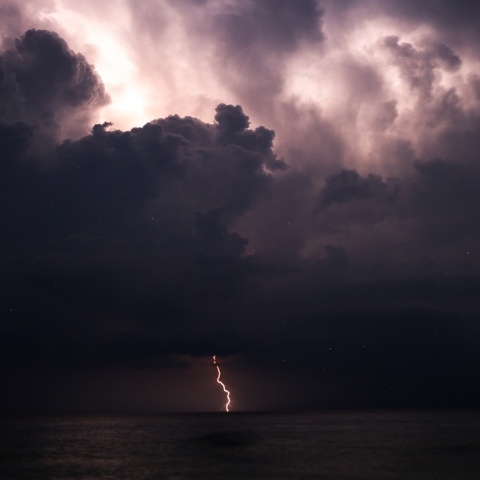 Αστραπή και μαύρα σύννεφα πάνω από τη θάλασσα