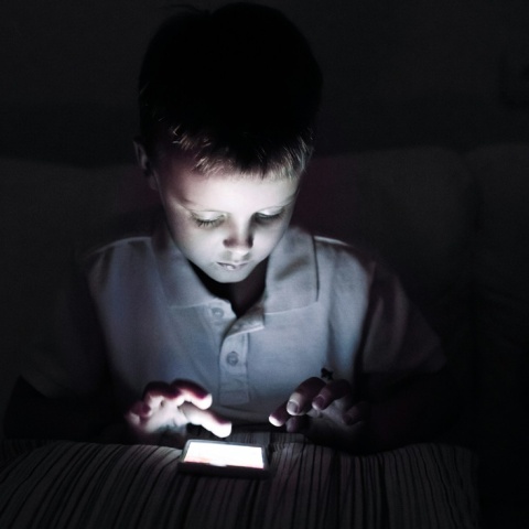 Παιδί με κινητό σε σκοτεινό δωμάτιο