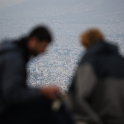 Δύο άτομο με φόντο τη συννεφιασμένη Αθήνα