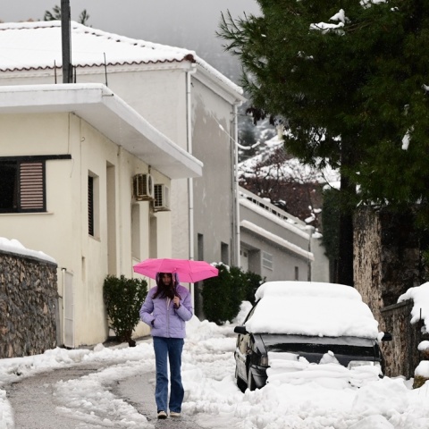 Δρόμος καλυμμένος με χιόνια και άτομο που περπατά με ανοιχτή ομπρέλα