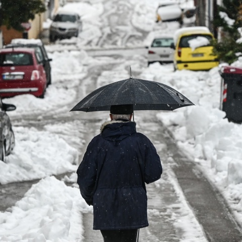 Άτομο περπατά με ομπρέλα μέσα στα χιόνια