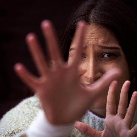 Γυναίκα με τρόμο στα μάτια προτάσσει τα χέρια της για να αντικρούσει επίθεση