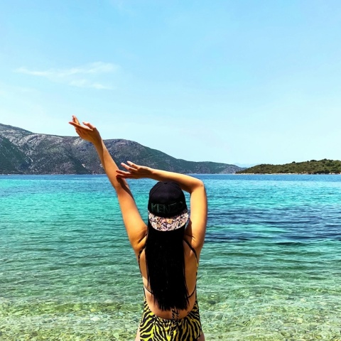 Γυναίκα τεντώνεται και απολαμβάνει τις διακοπές της με θέα τη θάλασσα