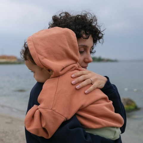 Μητέρα με παιδί αγκαλιά στην ακρογυαλιά