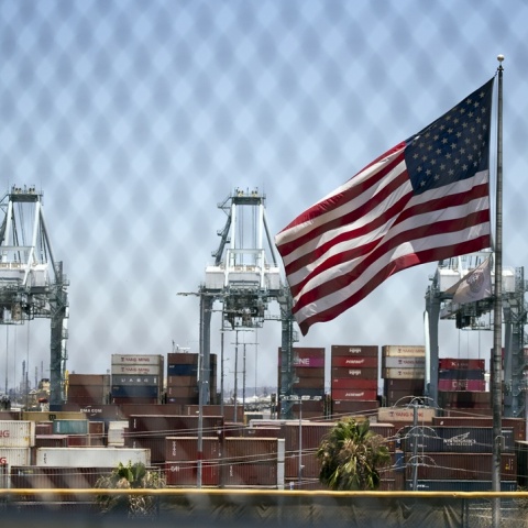 Κοντέινερ με προϊόντα και μπροστά τους η αμερικανική σημαία