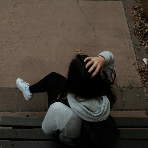 Πλάτη κοπέλας που κάθεται στο παγκάκι