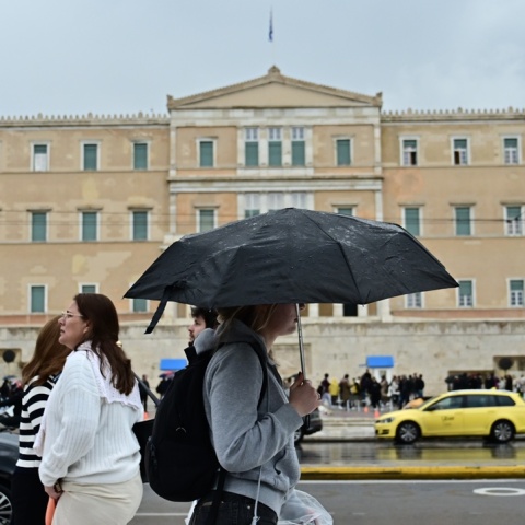 Πολίτες με ομπρέλα προστατεύονται από τη βροχή στο κέντρο της Αθήνας