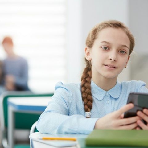 Νεαρή μαθήτρια με το κινητό ανά χείρας