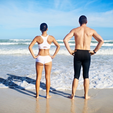 Γυναίκα και άνδρας με γυρισμένη την πλάτη στον φακό σε παραλία 