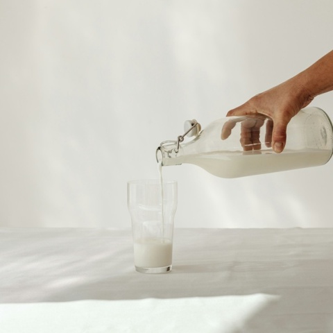 Ποτήρι με γάλα και μπουκάλι με γάλα σε λευκό φόντο