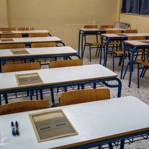 Θρανία σε εξεταστικά κέντρα με το τετράδιο απαντήσεων των Πανελληνίων 2025 τοποθετημένο πάνω τους