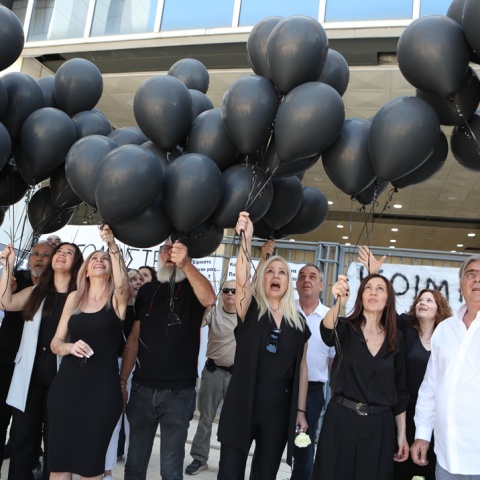 Συγγενείς θυμάτων και εγκαυματιών κρατούν μαύρα μπαλόνια έξω από το Εφετείο Αθηνών 
