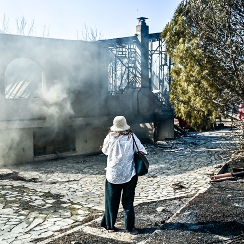 Γυναίκα μπροστά από καμένο σπίτι στην Παλαιά Φώκαια