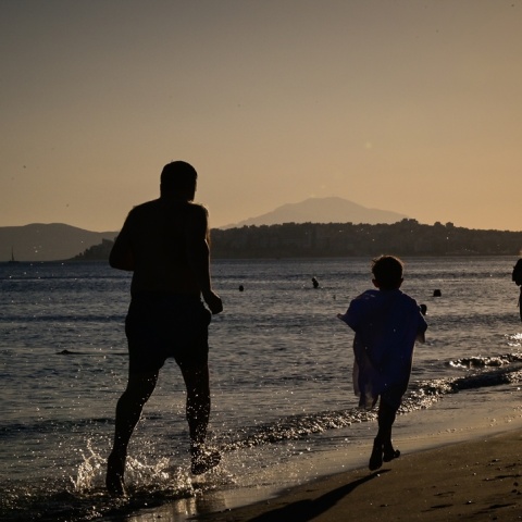 Πατέρας και παιδί που τρέχουν στην ακροθαλασσιά αναζητώντας λίγες στιγμές δροσιάς εν μέσω καύσωνα