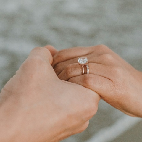 Χέρι άνδρα κρατά χέρι γυναίκας με δαχτυλίδι, εικόνα που μας δείχνει ότι έγινε πρόταση γάμου