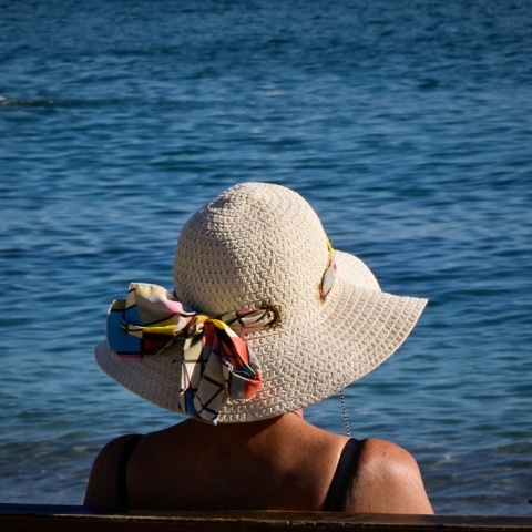 Γυναίκα με καπέλο κάθεται σε παγκάκι εν μέσω καύσωνα