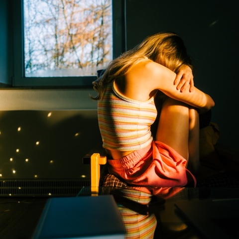 Γυναίκα κρύβει το πρόσωπό της και έχει στάσει σώματος αντίθετη από τον φωτογραφικό φακό