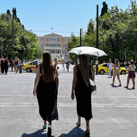 Γυναίκες με ομπρέλες προστατεύονται από τον ήλιο εν μέσω καύσωνα