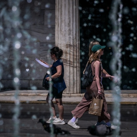 Πολίτες περπατούν πίσω από σιντριβάνι