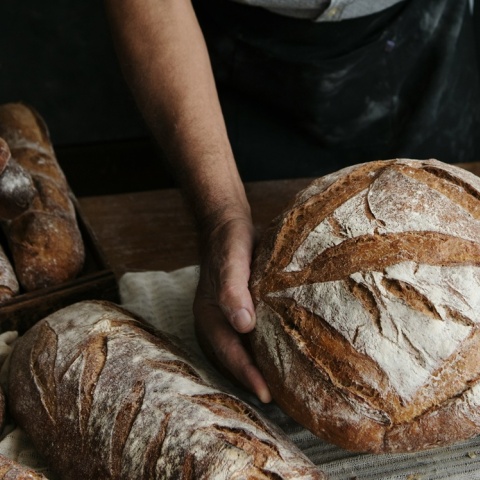 Άτομο κρατά καρβέλι ψωμί στα χέρια του