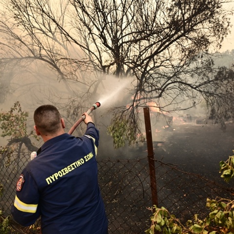Πυροσβέστης με τη μάνικα ανά χείρας επιχειρεί για την κατάσβεσης φωτιάς