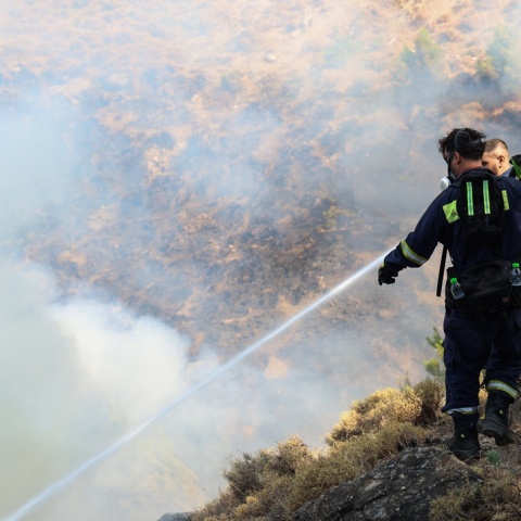 Πυροσβέστης με τη μάνικα ανά χείρας επιχειρεί για την κατάσβεσης φωτιάς
