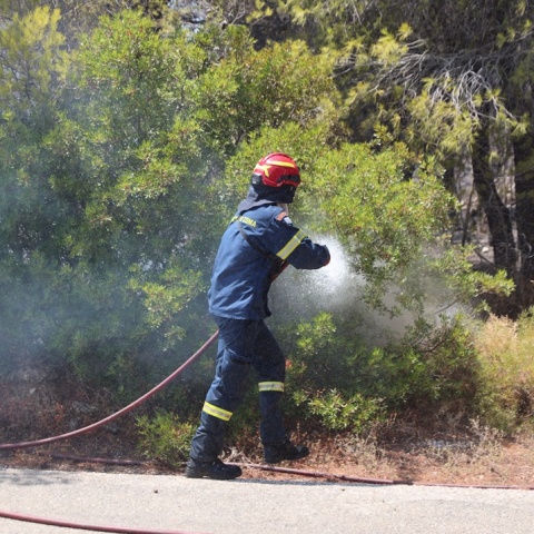 Πυροσβέστης με τη μάνικα ανά χείρας επιχειρεί για την κατάσβεσης φωτιάς