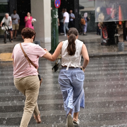 Βροχές και πολίτες που περπατούν στον δρόμο υπό βροχή