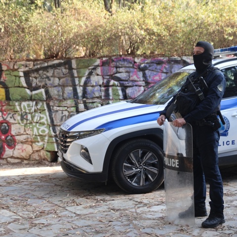 Αστυνομικός με την εξάρτισή του δίπλα από περιπολικό