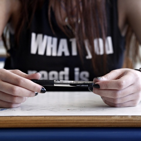 Μαθήτρια κρατά στυλό ενώ κάθεται στο θρανίο της