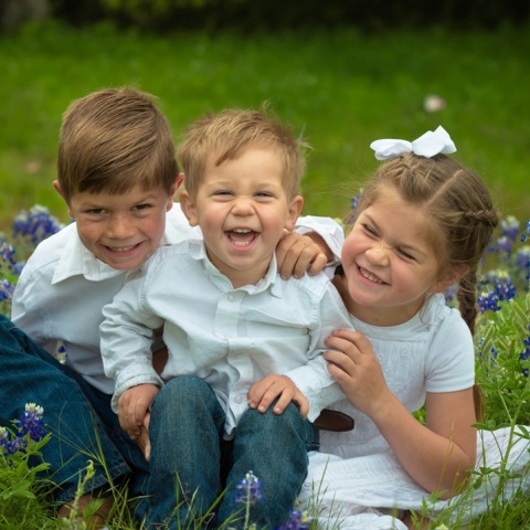 Τρία παιδιά ποζάρουν χαμογελαστά στον φακό