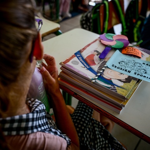 Μαθήτρια κάθεται στη θέση της έχοντας τα βιβλία της μπροστά της πάνω στο θρανίο και σημειώματα για καλή σχολική χρονιά