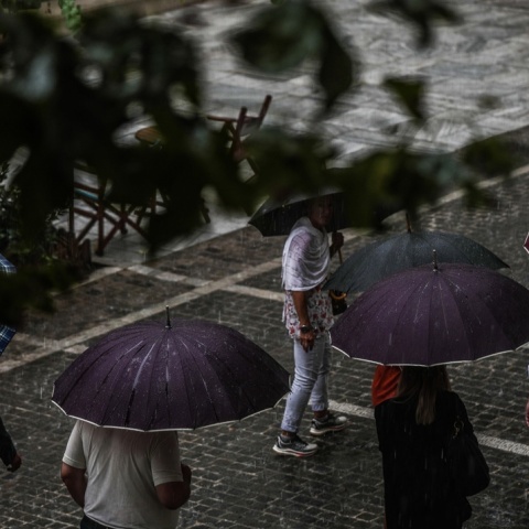 Πολίτες με ομπρέλες εν μέσω βροχής
