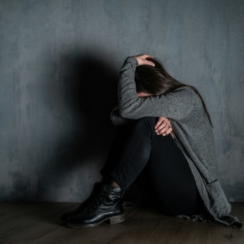 Γυναίκα που στέκεται κουλουριασμένη μακριά από τον κακοποιητή της