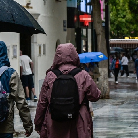 Πολίτες με ομπρέλες προστατεύονται από τη βροχή