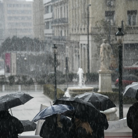 Πολίτες εν μέσω βροχής στην πλατεία Κοραή στην Αθήνα