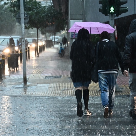 Πολίτες περπατούν εν μέσω βροχής σε δρόμο της Αθήνας