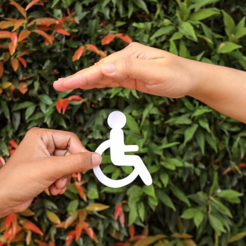 Ένα χέρι κρατάει το σήμα των ΑμεΑ και ένα άλλο το προστατεύει