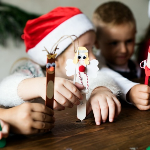 Παιδιά με χριστουγεννιάτικα σκουφιά κρατούν χριστουγεννιάτικα στολίδια