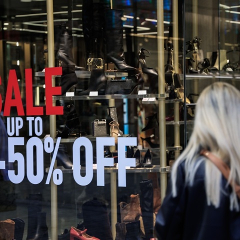 Γυναίκα μπροστά από βιτρίνα καταστήματος με αναφορά στις χειμερινές εκπτώσεις