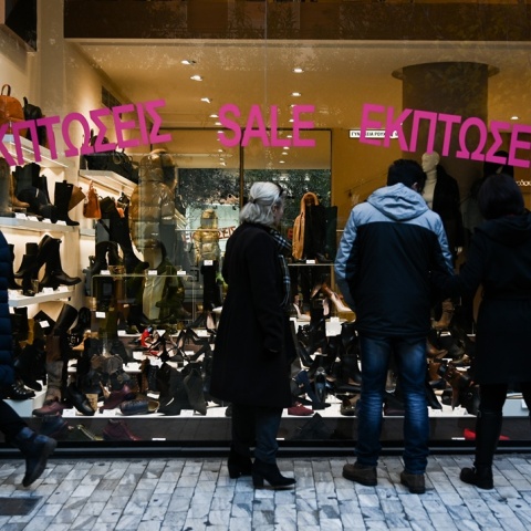 Βιτρίνα με ταμπέλα για χειμερινές εκπτώσεις και κόσμος που βλέπει τα προϊόντα