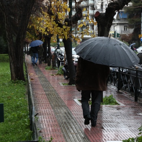 Πολίτες με ομπρέλα εν μέσω βροχής 