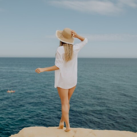 Γυναίκα με καπέλο μπροστά στη θάλασσα