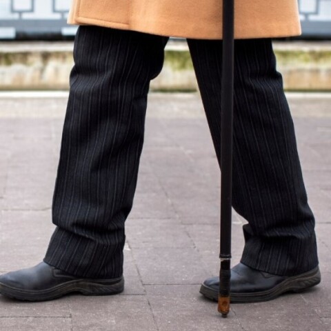 Συνταξιούχος περπατά με μπαστούνι στην πόλη