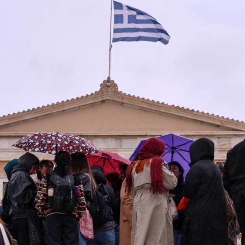Πολίτες με ομπρέλες υπό βροχή μπροστά από τη Βουλή