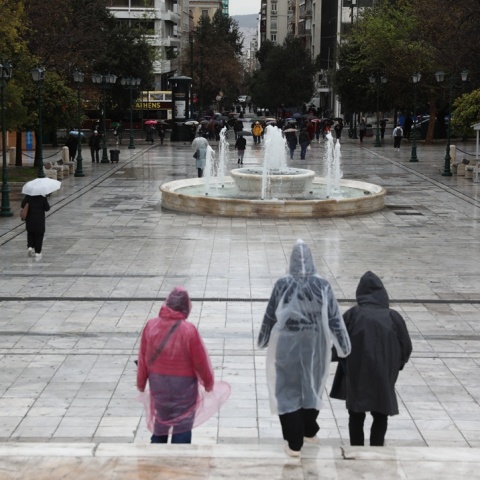 Πολίτες με αδιάβροχα στην πλατεία Συντάγματος